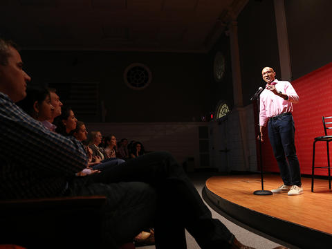 Man on stage with microphone with audience at Double Take event